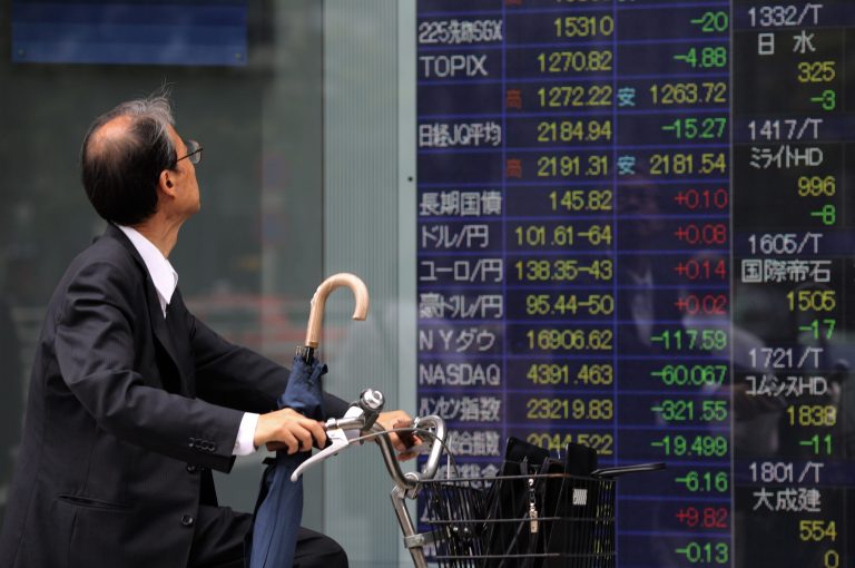 A man looks at an electronic stock board of a securities firm in Tokyo, Wednesday, July 9, 2014. Asian stock markets fell for a third day Wednesday as caution spread ahead of corporate earnings and after record highs on Wall Street. (AP Photo/Eugene Hoshiko)