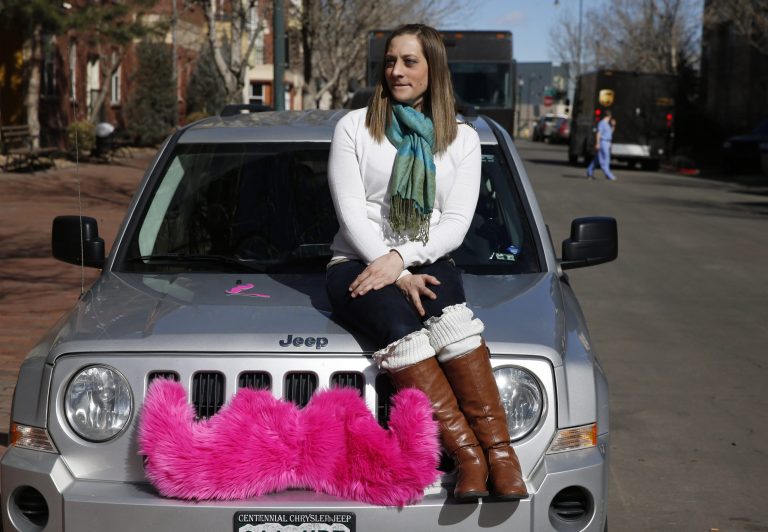 FILE - In this Feb. 28, 2014 file photo, part time Lyft driver Brittany Cameron sits on the hood of her own vehicle, which she uses to give rides, and which is adorned with Lyft's trademark pink mustache, in downtown Denver. Lyft is a transportation network company whose mobile-phone application facilitates peer-to-peer ride sharing by enabling passengers who need a ride to request one from drivers who have a car. Internet companies like Lyft that connect riders to drivers with a few taps on a cellphone app will be regulated in Colorado with legislation soon to become law, putting the state at the forefront of a push to try to legitimize the flourishing tech startups. (AP Photo/Brennan Linsley)