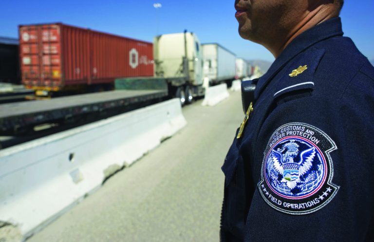 A U.S. Customs and Border Protection officer stands next to a line of trucks entering from Mexico at the Otay Mesa Cargo Port of Entry in San Diego, Calif., on May 23. (David Maung/Bloomberg)