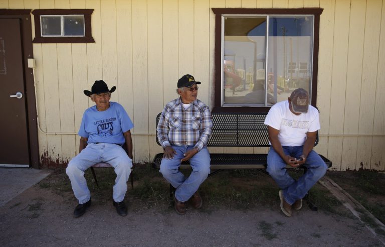 From left, Dennis Niez Sr., Ray Curley and Charley Singer sit in the shade at Little Singer Community School Thursday, Sept. 25, 2014, on the Navajo Nation in Birdsprings, Ariz. The Navajo Nation is poised to receive $554 million from the federal government over mismanagement of tribal resources in the largest single settlement of it's kind for a single America Indian tribe. (AP Photo/John Locher)