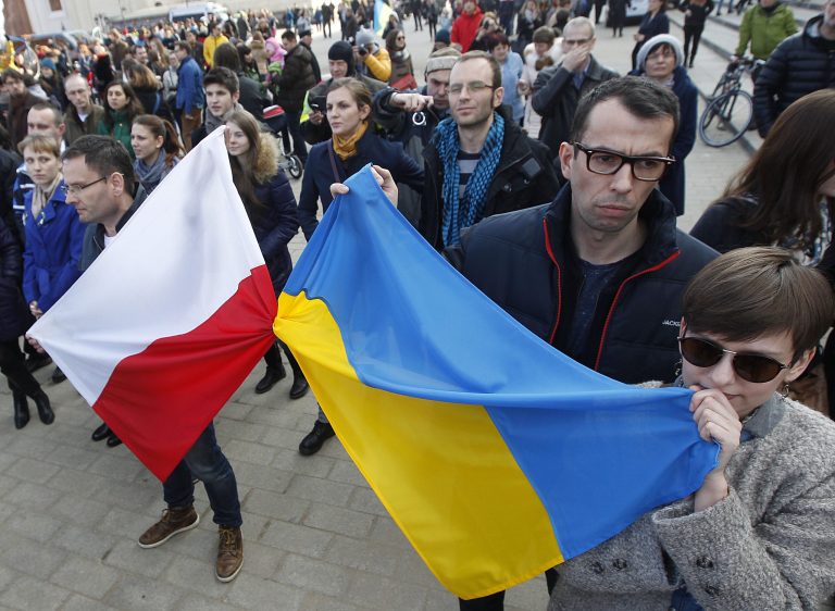 In this photo taken on Sunday, Feb. 23, 2014, people holding a Poland flag, left, and a Ukraine flag listen to speakers during a demonstration in Warsaw, Poland showing their support for protesters in Ukraine. Broken promises of help from the West. A tragic history of Russian invasion that goes back centuries. A painful awareness that conflicts in this volatile region are contagious. These are the factors that make nations across Eastern Europe watch events in Ukraine. Some countries like Poland, which shares a border with both Ukraine and Russia, are already starting to take precautionary measures. Polish Prime Minister Donald Tusk has warned that instability in Ukraine may be prolonged and lead Warsaw to upgrade its weapons. (AP Photo/Czarek Sokolowski)
