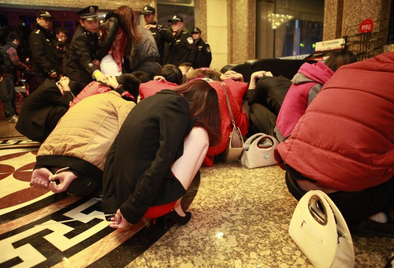 In this photo taken Sunday Feb. 9, 2014, detained suspects are gathered in a lobby during an anti-prostitution raid at a hotel in Dongguan in south China's Guangdong province. China's booming sex industry may finally be entering a winter after decades of robust growth, as Beijing wages a harsher-than-usual clampdown on vice. (AP Photo) CHINA OUT ONLINE OUT