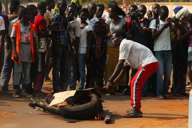 EDS NOTE GRAPHIC CONTENTS In this Sunday, Jan. 19, 2014 photo, a young man adds kindling to the burning body of a lynched Muslim man, in Bangui, Central African Republic. Residents of the Sango neighborhood, who said they were acting in revenge for the lynching of a taxi driver from Sango a day earlier, killed two Muslim men on Sunday, burning their bodies at a central roundabout. Two other Muslim passerbys escaped to the protection of French and African peacekeeping forces. (AP Photo/Herve Serefio)