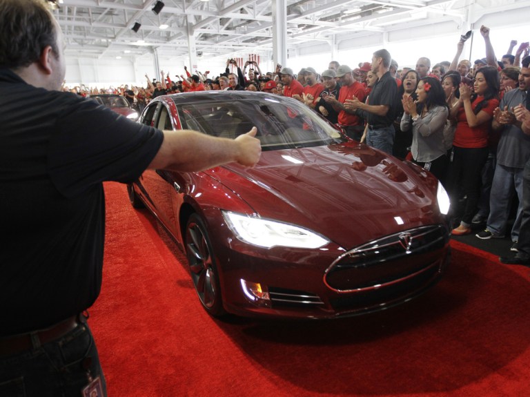 Tesla workers cheer one of the first Model S cars sold. Founder Elon Musk says Saudi Arabi's sovereign wealth fund may back his efforts to convert the carmaker to a private company. 
