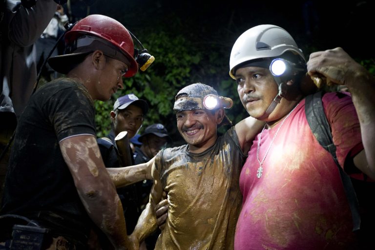 A rescued miner, center, is greeted by another miner while being helped by a rescue worker as he leaves the El Comal gold and silver mine in Bonanza, Nicaragua, Friday, Aug. 29, 2014.  The first 11 of 24 freelance gold miners trapped by a collapse in a mine have been rescued and crews were working early Saturday to free more, officials said. (AP Photo/Esteban Felix)