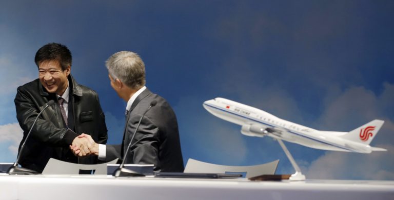 Song Zhiyong, left, president of Air China, shakes hands with John Wojick, right, senior vice president of global sales and marketing for Boeing Commercial Airplanes, after Wojick presented him with a leather flight jacket during a delivery ceremony for the first Boeing 747-8 Intercontinental airplane to be delivered to Air China, Monday, Sept. 29, 2014, in Everett, Wash. (AP Photo/Ted S. Warren)
