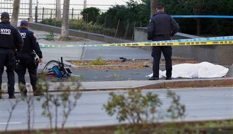 A New York Police Department officer stands next to a body covered under a white sheet near a mangled bike along a bike path Tuesday Oct. 31, 2017, in New York. (AP Photo/Bebeto Matthews)