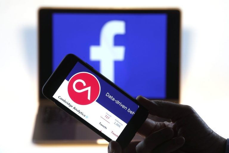 The verified Twitter Inc. page of Cambridge Analytica, displaying their logo and company name, sit on an Apple Inc. iPhone against a backdrop of the Facebook Inc. sign shown on a computer screen in this arranged photograph in London, U.K. Facebook's co-founder and chief executive officer, Mark Zuckerberg, has been called to appear before a House panel as fallout continues from revelations that Cambridge Analytica had siphoned data from some 50 million Facebook users as it built a election-consulting company that boasted it could sway voters in contests all over the world.
