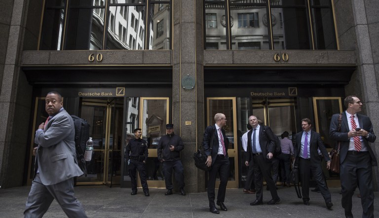 People stand outside Deutsche Bank AG headquarters on Wall Street in New York.
