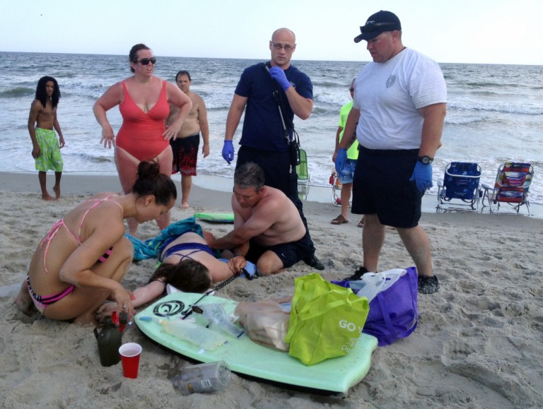People assist a teenage girl at the scene of a shark attack in Oak Island, N.C., Sunday, June 14, 2015. (AP Photo)Â 