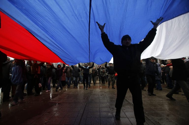 Pro-Russian demonstrators march with a huge Russian flag during a protest in front of a local government building in Simferopol, Crimea, Ukraine, Thursday, Feb. 27, 2014. Ukraine's acting interior minister says Interior Ministry troops and police have been put on high alert after dozens of men seized local government and legislature buildings in the Crimea region. The intruders raised a Russian flag over the parliament building in the regional capital, Simferopol, but didn't immediately voice any demands. (AP Photo/Darko Vojinovic)