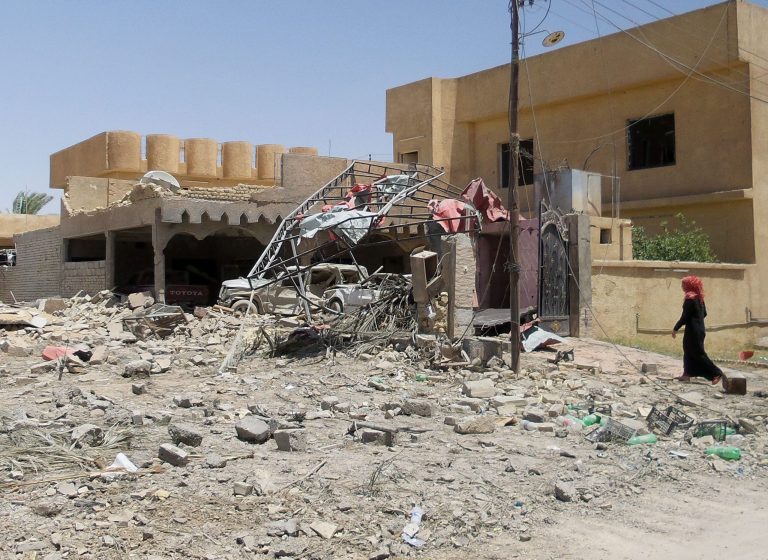 In this photo taken on Tuesday, July 1, 2014 an Iraqi woman inspects her damaged house after clashes between fighters of the al-Qaida-inspired Islamic State of Iraq and the Levant and Iraqi security forces in central Tikrit, 80 miles (130 kilometers) north of Baghdad, Iraq. The Islamic State of Iraq and the Levant announced this week that it has unilaterally established a caliphate in the areas under its control. It declared the group's leader, Abu Bakr al-Baghdadi, the head of its new self-styled state governed by Shariah law and demanded that all Muslims pledge allegiance to him. (AP Photo)