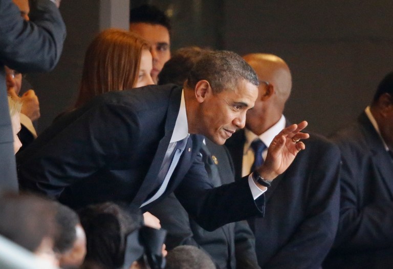 President Barack Obama waves to the crowd from the stands as he arrives for the memorial service for former South African President Nelson Mandela at the FNB stadium in Johannesburg, South Africa Tuesday, Dec. 10, 2013. (AP Photo/Ben Curtis)