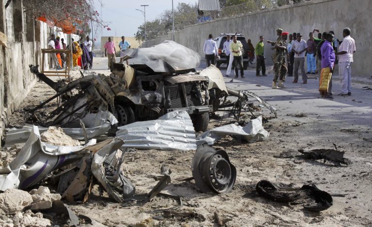 Somalis gather near the wreckage of one of the vehicles used for a car bomb, following a militant attack on the presidential palace in Mogadishu, Somalia Friday, Feb. 21, 2014. Nine al-Shabab militants wearing military fatigues and carrying guns and grenades died after attacking the presidential palace with two car bombs on Friday, in an assault the president called a 