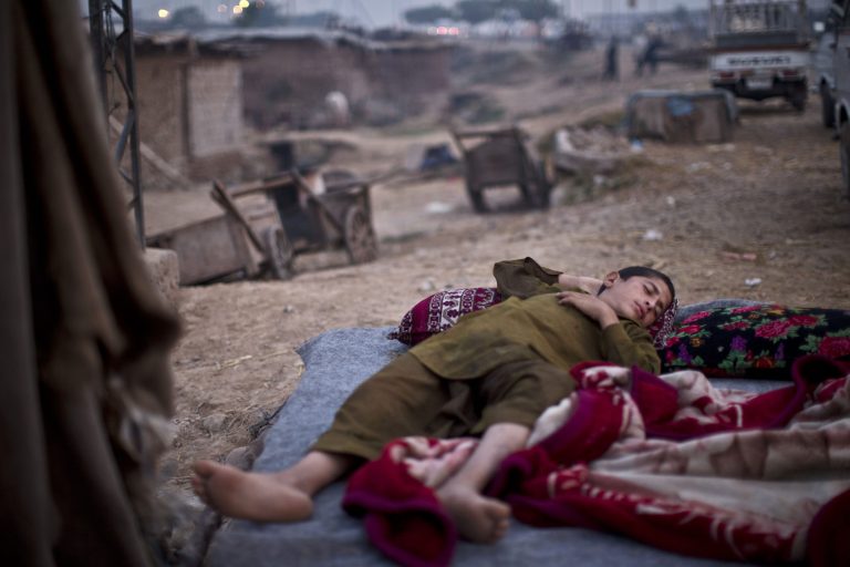 A Pakistani youth, who was displaced with his family from Pakistan's tribal region of Mohmand Agency due to fighting between the Taliban and the army, sleeps on the ground near his family's makeshift home on the outskirts of Islamabad, Pakistan, early Friday, Oct. 3, 2014. (AP Photo/Muhammed Muheisen)