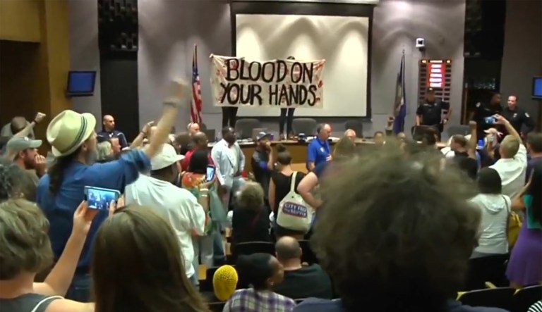 Police were called as protesters, angered that city officials in their estimation did little to intervene during the protests, overtook the meeting. (Image courtesy screenshot)