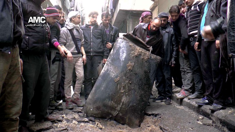 FILE - This January 19, 2014, file photo provided by Aleppo Media Center (AMC), an anti-Bashar Assad activist group, which has been authenticated based on its contents and other AP reporting, shows Syrian citizens inspecting an unexploded barrel bomb filled with explosives, which was dropped from a Syrian forces helicopter on a street in Aleppo, Syria. The use of barrel bombs has spread this year from Syria to Iraq, raising concerns that desperate governments in a number of unstable nations from Europe to Africa to the Middle East will turn to weapons that the international community has condemned as a violation of human rights laws.  (AP Photo/Aleppo Media Center, AMC, File)