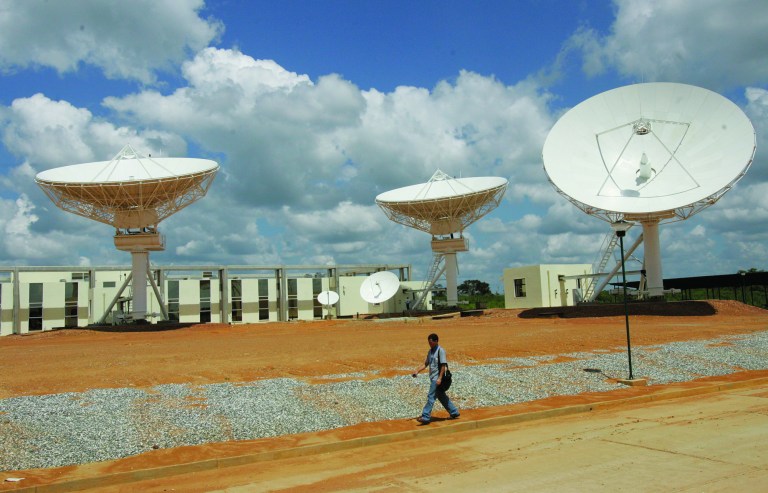 FILE - In this Oct. 28, 2008 file photo, a man walks past a satellite dish station in El Sombrero, Venezuela. The Venezuelan government said a satellite developed and launched in China for Venezuela will guarantee the South American country's autonomy in telecommunications. Chinese money is breathing life into government infrastructure projects that otherwise might have died for lack of financing. (AP Photo/Howard Yanes, File)