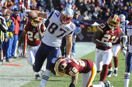 New England Patriots tight end Rob Gronkowski, center, is tackled by Washington Redskins cornerback Josh Wilson (26) as Washington Redskins strong safety DeJon Gomes (24) and Washington Redskins cornerback DeAngelo Hall (23) look on during the first half on Sunday, Dec. 11, 2011 in Landover, Md.