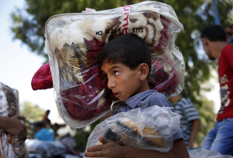 A Palestinian youth carries blankets donated to the United Nations school where hundreds of families sought refuge after fleeing their homes due to heavy Israeli missile strikes in Gaza City, Wednesday, July 23, 2014. Hundreds of thousands of Palestinians have fled their homes and are staying in 77 UN shelters, according to UNRWA, the U.N. refugee agency for Palestinians. The number of people who have been forced to seek shelter has increased nearly six-fold since the start of Israel's ground operation. (AP Photo/Lefteris Pitarakis)