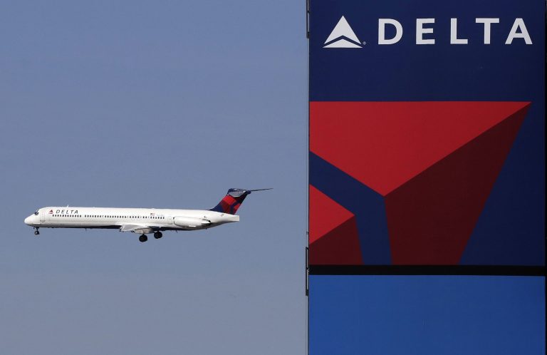A Delta Air Lines jet flies past the company's billboard at Citi Field in New York. (AP Photo/Mark Lennihan)