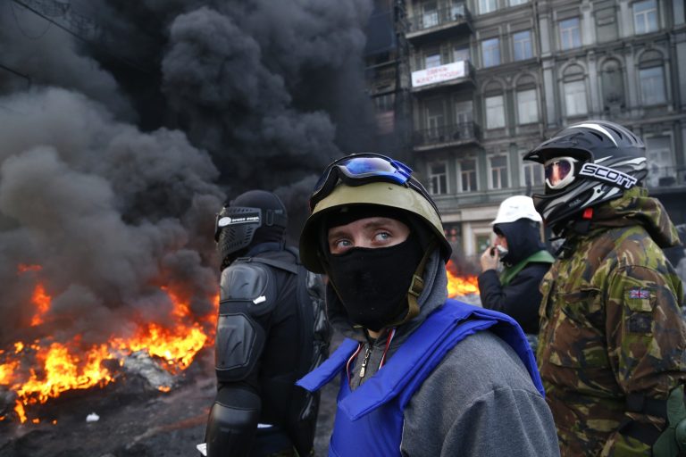 Protesters stand behind the barricade in front of riot police in central Kiev, Ukraine, Saturday Jan. 25, 2014. Ukraine's Interior Ministry has accused protesters in Kiev of capturing two of its officers as violent clashes have resumed in the capital and anti-government riots spread across Ukraine.  (AP Photo/Sergei Grits)