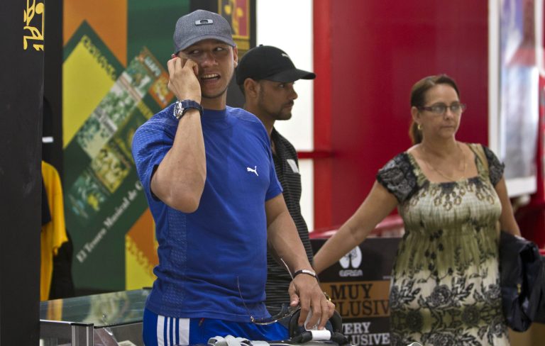 In this May 29, 2014 photo, Yulieski Gourriel, player for the Cuban baseball team Industriales, speaks on his cell phone before catching his flight at the Jose Marti International Airport in Havana, Cuba. Gourriel left Cuba to join the DeNA BayStars of Yokohama, Japan. New rules let islanders play overseas as long as they fulfill their commitment to the domestic league and international competitions. Gourriel is scheduled to be back for Cuba's winter league in November. (AP Photo/Franklin Reyes)