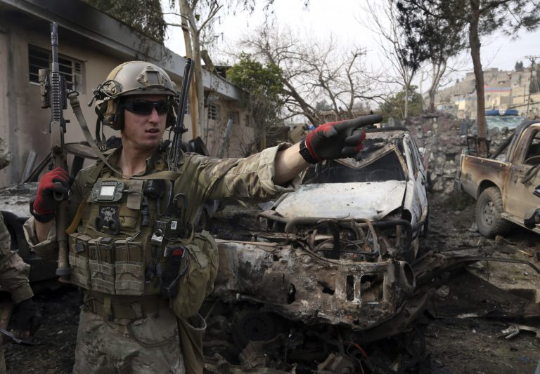 A U.S. soldier stands at the site where a suicide bombers have attacked a police compound in Surobi district of Kabul, Afghanistan, Friday, Feb. 21, 2014. Afghan officials said suicide bombers have attacked a police compound in a mountainous area near the capital, Kabul. (AP Photo/Rahmat Gul)