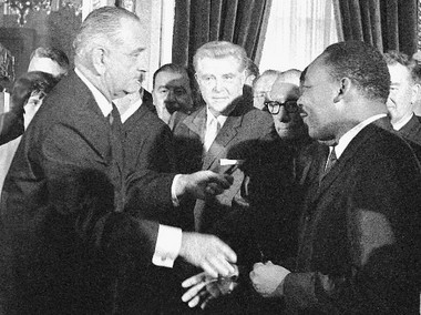 President Lyndon Johnson reaches to shake the hand of the Rev. Martin Luther King Jr. after signing the Voting Rights Act on Aug. 6, 1965. (AP file photo)
