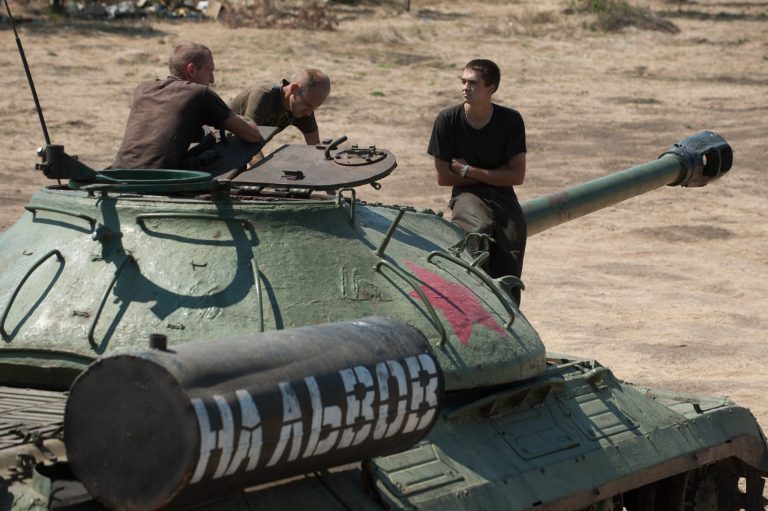 Ukrainian government soldiers sit atop of a tank with the words reading 