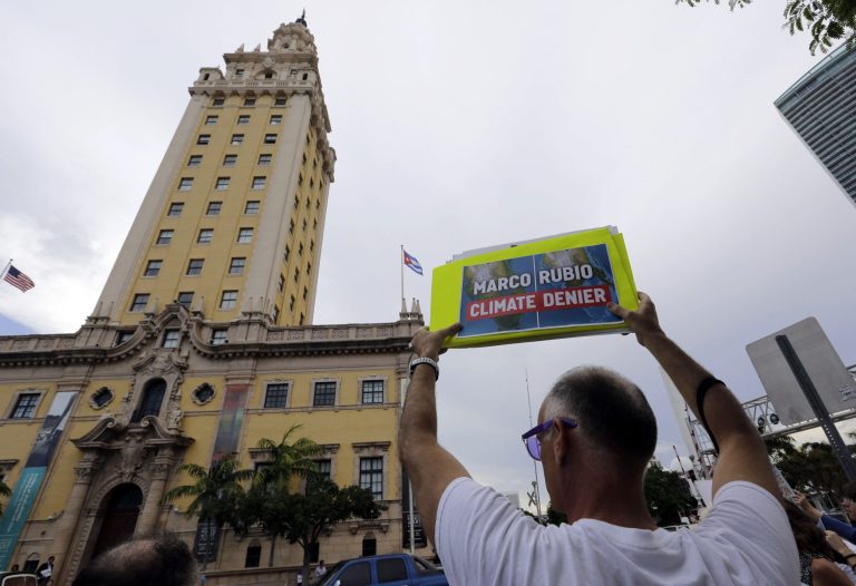 Jim Harper, of Miami, holds a sign reading 