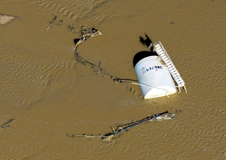 File - In this Sept. 17, 2013, file photo, a crude oil storage tank lies on its side in flood water along the South Platte River in Weld County, Colo. Oil and gas regulators are discussing whether to create new rules after more than a dozen spills of petroleum products were blamed on major flooding last September. (AP Photo/John Wark, file)