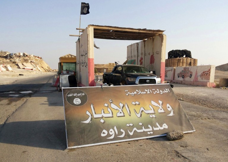 FILE - In this Tuesday, July 22, 2014, file photo, a sign is posted at a checkpoint belonging to the Islamic State group, captured from the Iraqi Army, at the main entrance of Rawah, 175 miles (281 kilometers) northwest of Baghdad, Iraq. Arabic reads, 