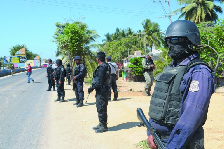 State police stand at a roadblock due to stepped up security after masked armed men broke into a beach home, raping six Spanish tourists who had rented the house in Acapulco, Mexico, Tuesday Feb. 5, 2013. According to the mayor of Acapulco, five masked men burst into a house the Spaniards had rented on the outskirts of Acapulco, in a low-key area near the beach, and held a group of six Spanish men and one Mexican woman at gunpoint, while they raped the Spanish women before dawn on Monday. (AP Photo/Bernandino Hernandez)
