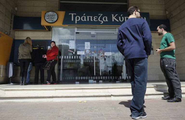 In this image taken Saturday, March 16, 2013, people queue to use an ATM machine outside of Bank of Cyprus branch in southern port city of Limassol, Saturday, March 16, 2013. Many rushed to cooperative banks which are open Saturdays in Cyprus after learning that the terms of a bailout deal that the cash-strapped country hammered out with international lenders includes a one-time levy on bank deposits. The move, decided in an extraordinary meeting of the finance ministers of the 17-nation eurozone in the early hours Saturday, is a major departure from established policies. Analysts have warned that making depositors take a hit threatens to undermine investors' confidence in other weaker eurozone economies and might possibly lead to bank runs. (AP Photo/Pavlos Vrionides)