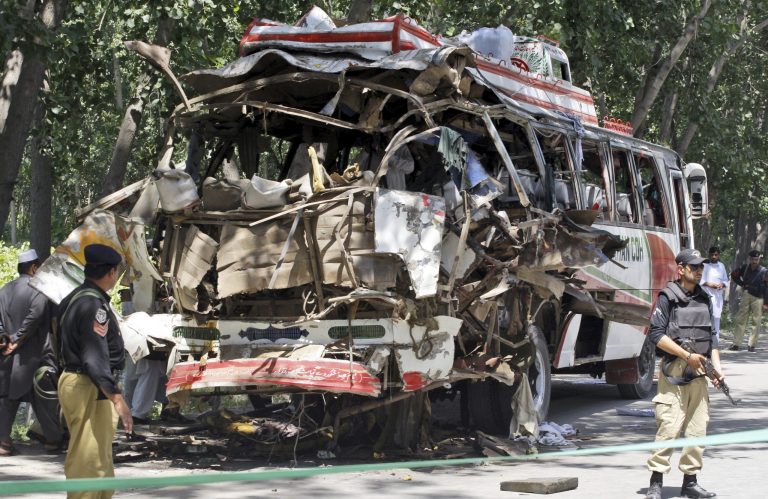   Pakistani policemen stand by the wreckage of a bus that exploded when a bomb planted in it went off on the outskirts of Peshawar, Pakistan, Friday, June 8, 2012. A bomb tore through a bus carrying government employees and other civilians in northwestern Pakistan killing several people in an attack that served as a reminder of the continued militant threat despite a significant drop in violence over the past year, officials said. (AP Photo/Mohammad Sajjad)  