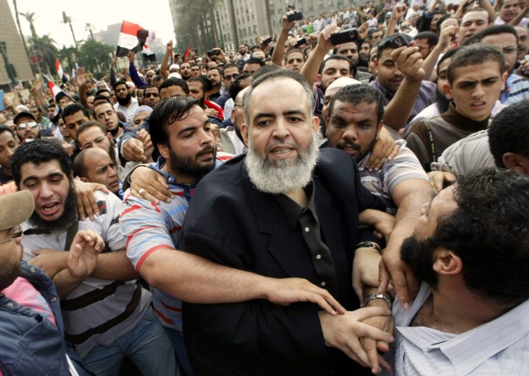 FILE - In this Friday, Oct. 28, 2011 file photo, Egyptian Muslim cleric and candidate for the Egyptian presidency Hazem Salah Abu-Ismail, center, is guarded by his supporters as he enters Tahrir Square during a protest against the ruling military council, in Cairo, Egypt. On Saturday, April 12, 2014, a court in Egypt sentenced Abu-Ismail, an ultraconservative Islamist who is an ally of ousted President Mohammed Morsi to one year in prison for insulting the judiciary during his trial. Abu-Ismail, a former presidential hopeful, is being tried for allegedly concealing the fact his mother was a U.S. citizen in order to qualify for the 2012 presidential election. (AP Photo/Amr Nabil, File)
