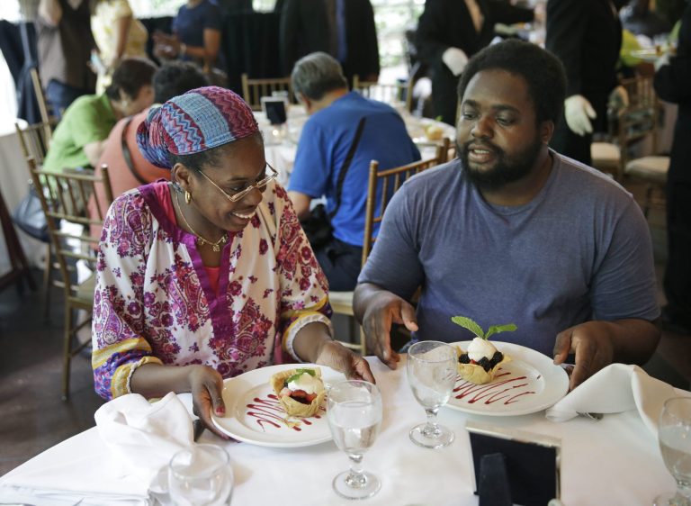 Sharon Robinson, left, and Roy Gantt, both residents of the New York City Rescue Mission, look over their just served desserts at The Loeb Boathouse restaurant in New York, Wednesday, June 25, 2014.  Recycling magnate Chen Guangbiao,  known for his sometimes eccentric gestures served up a fancy lunch Wednesday to hundreds of homeless New Yorkers at a Central Park restaurant and serenaded them with 