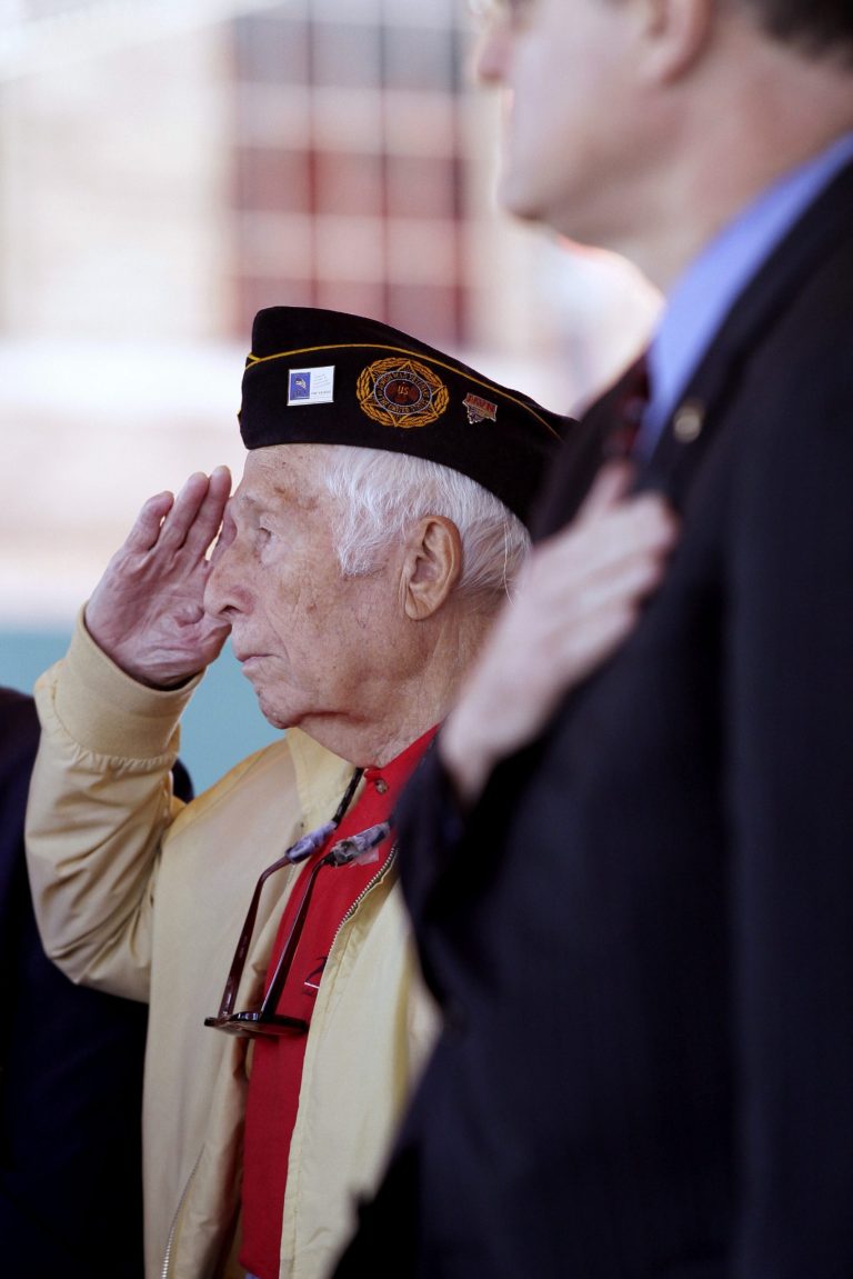 U.S. Navy World War II veteran Dr. Jerry Sherman, left, salutes during the playing of 