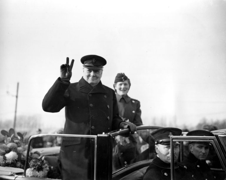 Winston Churchill holds up two fingers to make a V-sign for Victory as he salutes from an open car in Antwerp, Belgium, on Nov. 17, 1945.