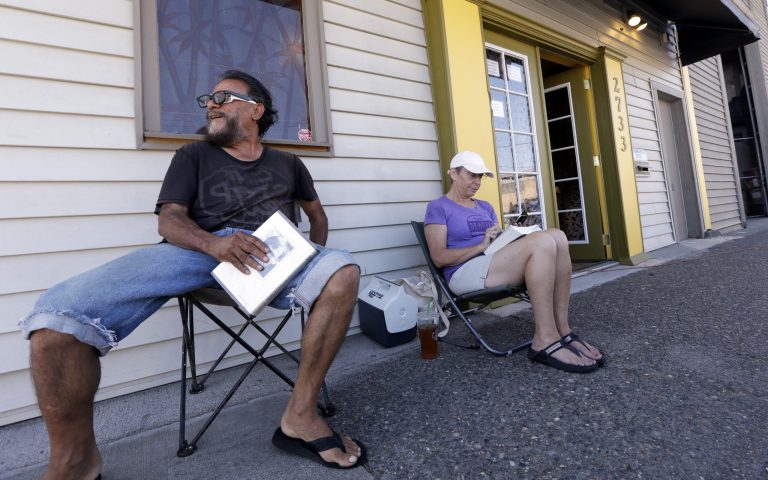 George Vargas, left, takes a seat next to first-in-line customer Deb Greene in front of the recreational marijuana store Cannabis City Monday, July 7, 2014, in Seattle. The store will be the first and only store initially in Seattle to legally sell recreational pot when sales begin Tuesday. (AP Photo/Elaine Thompson)
