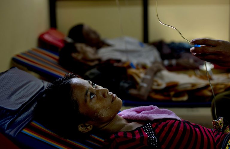 In this Aug 27, 2014 photo, a woman infected with HIV stares up at the hand of a volunteer as he adjusts her intravenous drip at a crowded clinic in South Dagon, on the outskirt of Yangon, Myanmar. This clinic admits around 10 new HIV/AIDS patients every month, many of them from the countryâs delta region in the south. (AP Photo/Gemunu Amarasinghe)