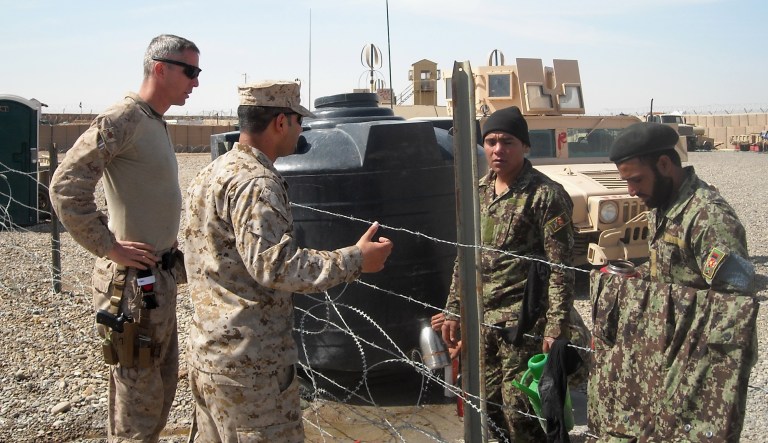This photo taken March 22, 2013 shows U.S. Marine Maj. Chris Bourbeau, left, with the 1st Brigade, 215th Corps Afghanistan National Army Advisor Team, and a translator, at Camp Garmser, Helmand province, in southern Afghanistan. Rescinding the Military Accessions Vital to the National Interest program could nullify enlistment contracts for approximately 1,000 people of the total 10,400 immigrants who were recruited for their medical and language skills. (AP Photo/Kimberly Dozier)