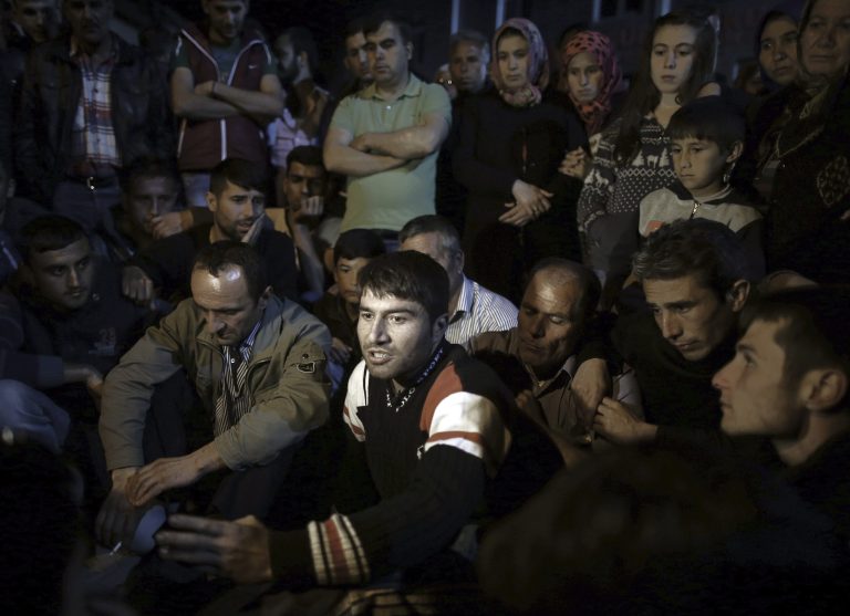 Miner Erdal Bicak, center, speaks to journalists as he joined fellow miners and their family members to commemorate the Soma mine accident victims and protest the government's labor policy in Savastepe , Turkey, late Friday, May 16, 2014. Public anger has surged in the wake of the Soma coal mine inferno that killed at least 299 miners. (AP Photo/Emrah Gurel)