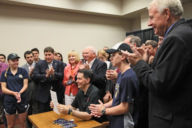 Wisconsin Gov. Scott Walker holds up the Bucks arena financing legislation, Senate Bill 209, after signing it at the Wisconsin State Fair in West Allis, Wis. (Michael Sears/Milwaukee Journal-Sentinel via AP)
