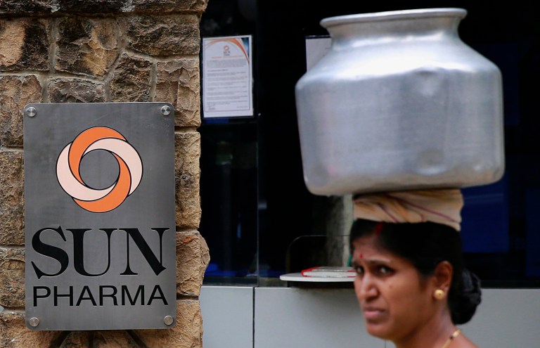 An Indian woman carries a water vessel as she walks past the office of Sun Pharmaceutical in Mumbai, India, Monday, April 7, 2014. The Sun Pharmaceutical Industries is buying troubled generic drugmaker Ranbaxy Laboratories in a $4 billion all-stock transaction, the companies said Monday. (AP Photo/Rafiq Maqbool)