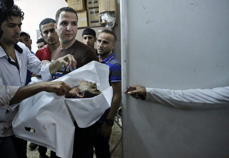 A Palestinian carries the body of a child at the morgue in Gaza City's Shifa hospital, in the northern Gaza Strip, Monday, July 28, 2014. An explosion killed 10 people, 9 of them children, at a park at Shati refugee camp, in northern Gaza Strip. Israeli and Palestinian authorities traded blame over the attack and fighting in the war raged on despite a major Muslim holiday. (AP Photo/Lefteris Pitarakis)