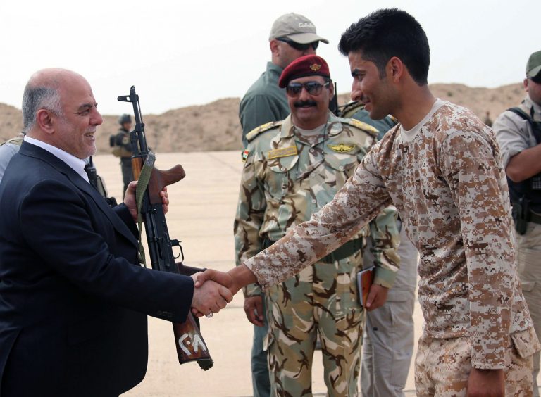 In this photo taken on Wednesday, April 8, 2015 Iraqi Prime Minister Haider al-Abadi, left, gives a rifle to a Sunni volunteer at a camp in Habaniyah, 80 kilometers (50 miles) west of Baghdad, Iraq. After victory against Islamic State militants in the city of Tikrit, Iraq's prime minister vowed, earlier in the week, to protect the people living in territories controlled by the Islamic State group from any retribution or rights violations when their lands are retaken by government forces. (AP Photo)
