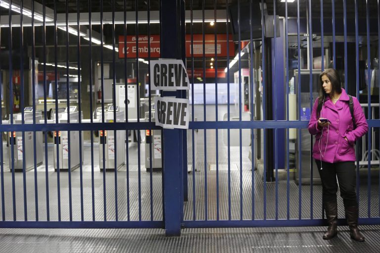 A passenger stands at the closed Belem metro station where a sign hangs that reads in Portuguese 