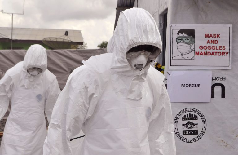Health workers wearing Ebola protective gear remove the body of a man that they suspect died from the Ebola virus, at a USAID, American aid Ebola treatment center at Tubmanburg on the outskirts of Monrovia, Liberia, Friday, Nov. 28, 2014. (AP Photo/ Abbas Dulleh)